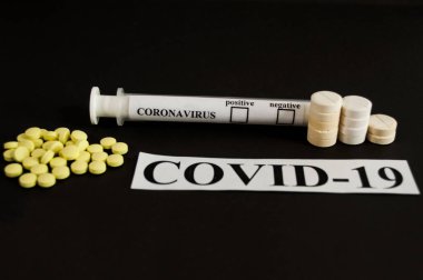 COVID-19 ilaçları - siyah arkaplanda test tüpleri ve tabletler