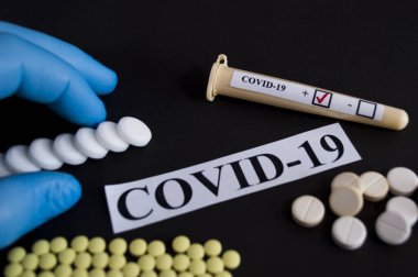 COVID-19 ilaçları - siyah arkaplanda test tüpleri ve tabletler