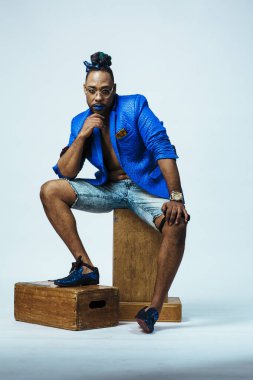 Mavi elbiseli ve mavi dudaklı bir adamın stüdyo portresi