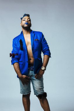 Mavi elbiseli ve mavi dudaklı bir adamın stüdyo portresi. Meditasyonlu