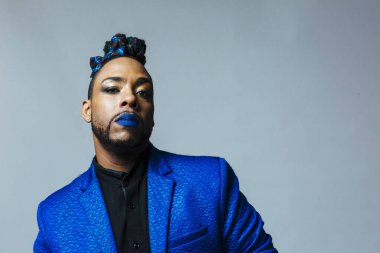 Mavi elbiseli ve mavi dudaklı bir adamın stüdyo portresi. Meditasyonlu