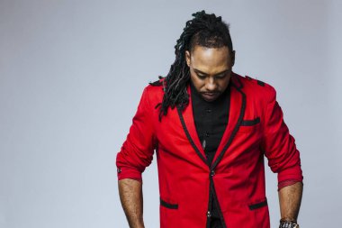 Kırmızı ceketli ve rastalı bir adamın stüdyo portresi