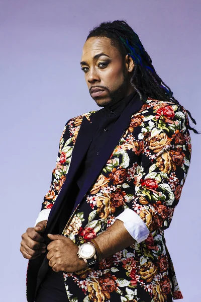 Retrato de estudio de un hombre con un traje con estampado de flores y rastas — Foto de Stock