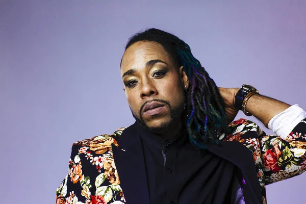 Retrato de estudio de un hombre con un traje estampado de flores y rastas jugando con su cabello — Foto de Stock