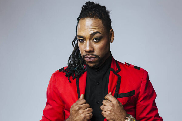 Студийный портрет человека в красном пиджаке и дредах
