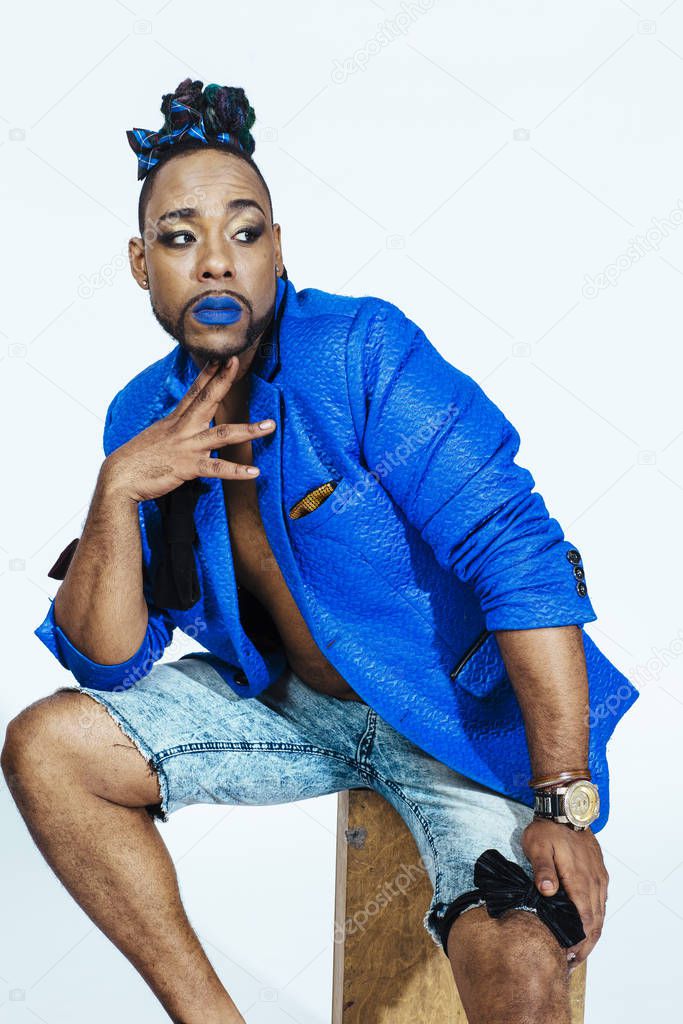 Studio portrait of a man with blue outfit and blue lips. Meditative
