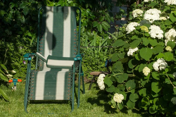 portable chair in the garden, comfortable chair, typically upholstered, with side supports for a person\'s arms.