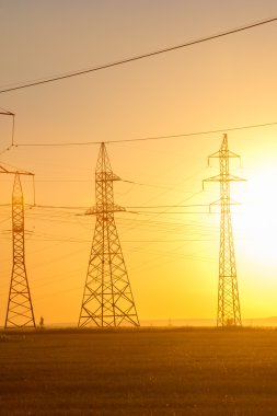 Yüksek gerilim enerji nakil hattı. Enerji ayağı. Gün batımı, şafakta. Elektrik