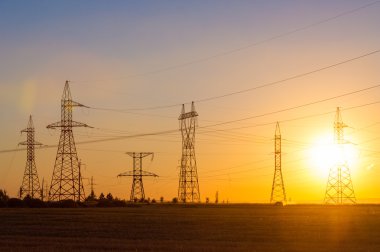 Yüksek gerilim enerji nakil hattı. Enerji ayağı. Gün batımı, şafakta. Elektrik
