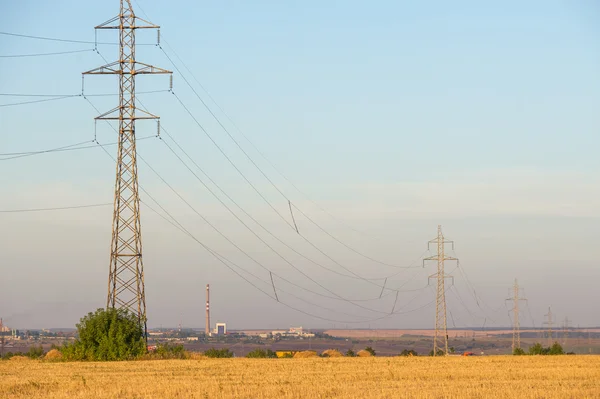 High-voltage power transmission line. Energy pillars. At sunset, — Stock Photo, Image