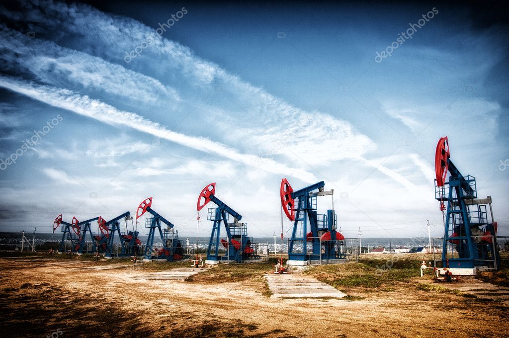 Oil and gas industry. Work of oil pump jack on a oil field. White clouds and blue sky. oil well pump. Oil and gas industry. Work of oil pump jack on a oil field.