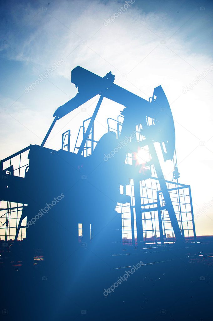 Oil and gas industry. Work of oil pump jack on a oil field. White clouds and blue sky. oil well pump. Oil and gas industry. Work of oil pump jack on a oil field.