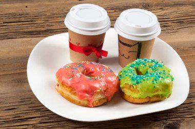 Doku, arka plan, iki çörek ve kahve. Çörek renkli buzlanma ile kaplı. Ahşap eski kurulları tezgah