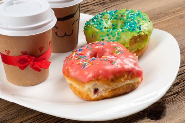 Doku, arka plan, iki çörek ve kahve. Çörek renkli buzlanma ile kaplı. Ahşap eski kurulları tezgah