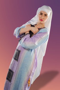 güzel bir kız, bir Müslüman. bir hijab giyen. Müslüman kız imajını kuran tutuyor. Güzel bir Müslüman kız dikey portresi. Bir kız Kur'an elinde