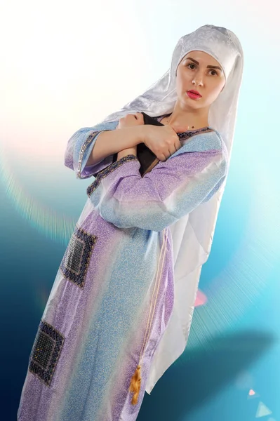 美丽的女孩 一个穆斯林 戴着头巾穆斯林女孩的形象是拿着高兰 一个美丽的穆斯林女孩的垂直肖像 在一个女孩的手中 — 图库照片