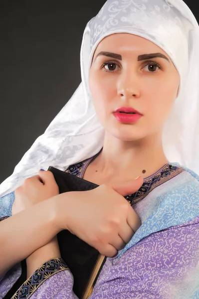 美しい少女 イスラム教徒 ヒジャーブを着ています イスラム教徒の少女のイメージは Qoran を保持しています 美しいイスラム教徒の少女の肖像画を垂直 コーランの少女の手の中 — ストック写真