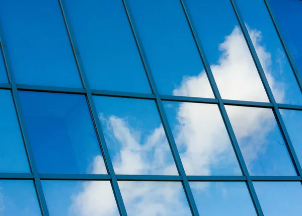 Texture, pattern, background. Reflection in building windows. Blue windows, clouds reflected in the windows