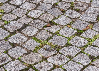 doku, arka plan. Granit taş kaldırım. Asfalt karayolu sokak. herhangi bir taş döşeli alan veya yüzey. Eski Arnavut kaldırımlı yol kaldırım doku, çim taşları arasında