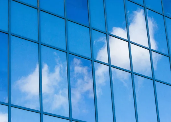 Texture, pattern, background. Reflection in building windows. Blue windows, clouds reflected in the windows