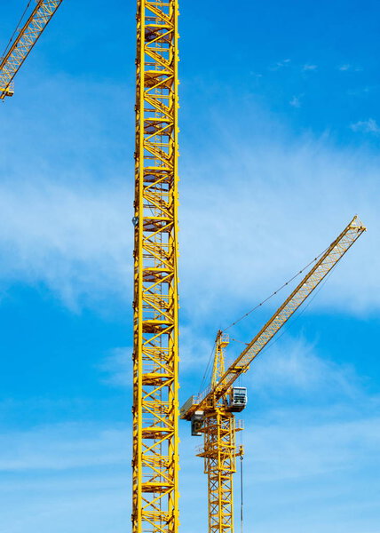 Texture, pattern, background. Tower cranes on the construction of residential buildings, painted with yellow paint