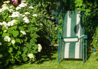 genellikle yan destekler bir kişinin silah ile doldurulmuş Bahçe, rahat sandalyede Portatif sandalye.