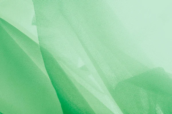 Doku, arka plan, desen. İpek kumaş dokusuna yeşildir. İpek kumaş saydamdır. İpek saten doku veya kadife malzeme dalgalı kırışıklıklar kumaş ya da sıvı dalga gösterimi 