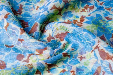 Doku, arka plan, desen. Kumaş krep de chine. Mavi beyaz pişmiş toprak yeşil. Kumaş üzerine boyalı çiçekler vardır. Soyut çizim