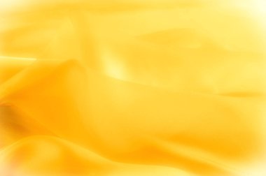 Fotoğraf bulanık. Doku, arka plan, desen. Sarı ipek kumaş. Arka plan lüks sarı kumaş ya da sıvı dalga veya dalgalı doku. Tüm arka plan.
