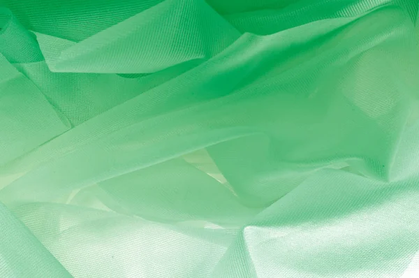 Texture, background, pattern. The texture of the silk fabric is green. Silk fabric is transparent. Fabric or liquid wave illustration of wavy creases of silk satin texture or velvet material