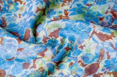 Doku, arka plan, desen. Kumaş krep de chine. Mavi beyaz pişmiş toprak yeşil. Kumaş üzerine boyalı çiçekler vardır. Soyut çizim