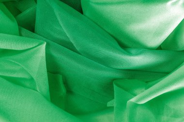 Doku, arka plan, desen. İpek kumaş dokusuna yeşildir. İpek kumaş saydamdır. İpek saten doku veya kadife malzeme dalgalı kırışıklıklar kumaş ya da sıvı dalga gösterimi 