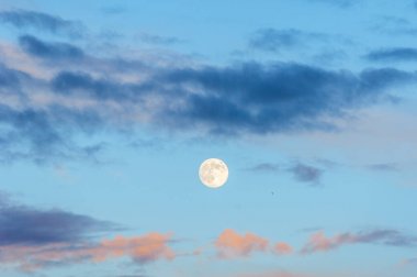 Gün batımında akşam manzara. Gökyüzünde dolunay ile. Şiddetli fırtına bulutları pastel tonları ile.