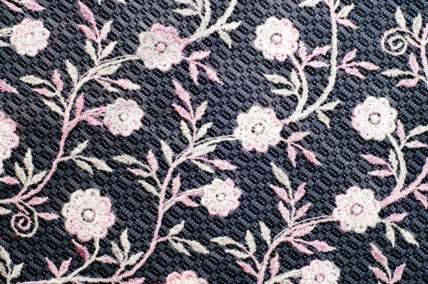 Texture, background, pattern. Pink lace decorated with flowers on a black background. Lace decorated with a pattern and decorative rose on a black background.