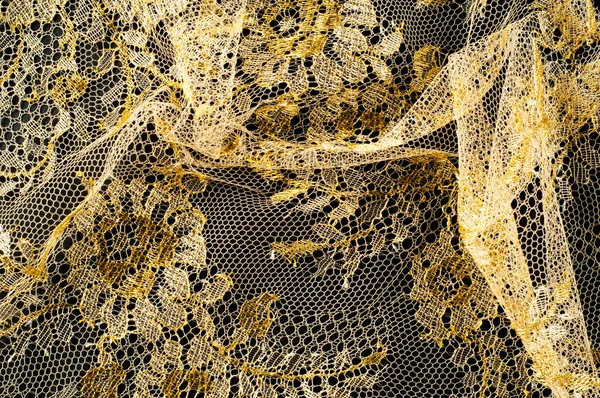 Image texture background, decorative gold lace with pattern. Golden vintage lacy background. Golden lace on a black background. Spandex, macro. Lacy decorative floral pattern.