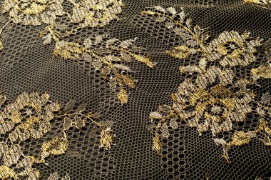 Resmi doku arka planı, dekoratif altın dantel desenli. Altın vintage dantelli arka plan. Siyah bir zemin üzerine altın dantel. Spandex, makro. Dantelli dekoratif çiçek desenli.