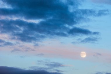 Gün batımında akşam manzara. Gökyüzünde dolunay ile. Şiddetli fırtına bulutları pastel tonları ile.