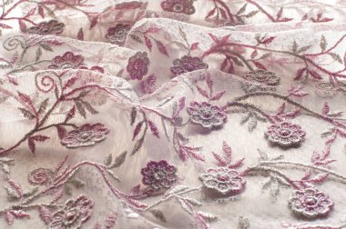 Doku, arka plan, desen. Pembe dantel çiçek üzerinde beyaz bir arka plan ile dekore edilmiştir. Arka planını çiçekler ile dekore edilmiş pembe dantel kumaş