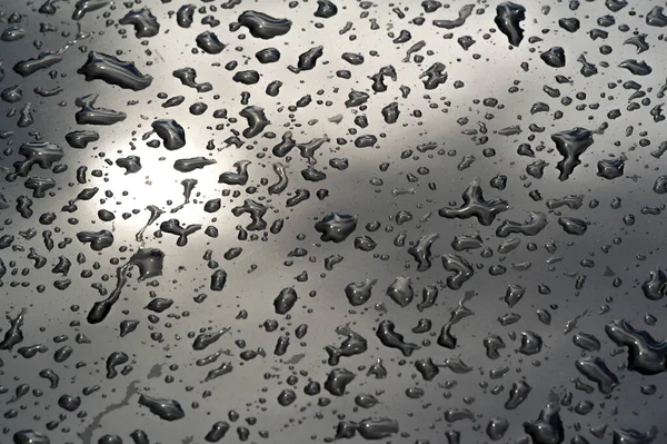 Lluvia de verano, gotas de agua en la pintura del coche. una pequeña ronda o p — Foto de Stock