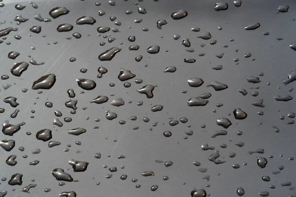 Lluvia de verano, gotas de agua en la pintura del coche. una pequeña ronda o p — Foto de Stock