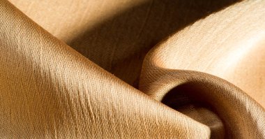 Arka plan, desen, doku, bej altın ipek kumaş Pürüzsüz mat bir kaplamaya sahiptir ve hafif bükümlü bir iplik sayesinde dayanıklıdır. Tasarımdan projelerinize kadar her şey için bu lüks kumaşı kullanın