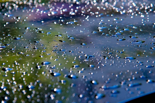 La foto está borrosa, gotas de lluvia en la pintura del coche — Foto de Stock