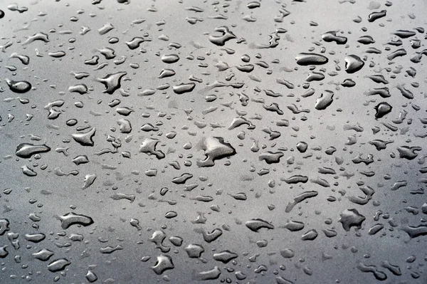 Lluvia de verano, gotas de agua en la pintura del coche. una pequeña ronda o p — Foto de Stock