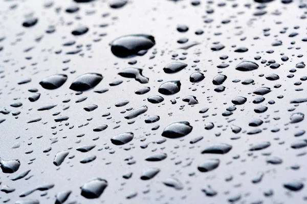 Lluvia de verano, gotas de agua en la pintura del coche. una pequeña ronda o p — Foto de Stock