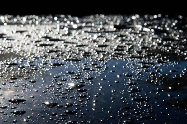 La foto está borrosa, gotas de lluvia en la pintura del coche — Foto de Stock