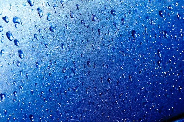 Lluvia de verano, gotas de agua en la pintura del coche. una pequeña ronda o p — Foto de Stock