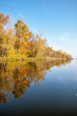 Sonbahar, sudaki ağaçların göldeki yansıması üzerine sessizdir.