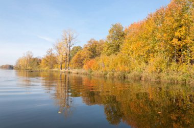 Sonbahar, sudaki ağaçların göldeki yansıması üzerine sessizdir.