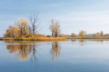 Sonbahar, sudaki ağaçların göldeki yansıması üzerine sessizdir.