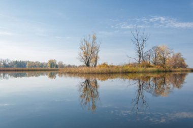 Sonbahar, sudaki ağaçların göldeki yansıması üzerine sessizdir.